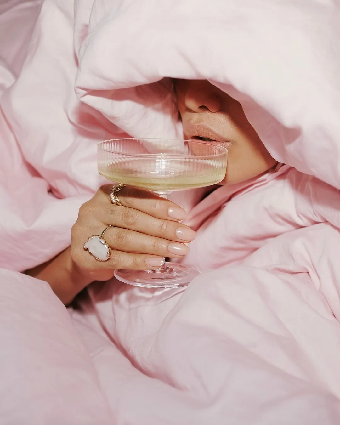 Woman with a champagne glass wrapped in pink MRFS bed linen