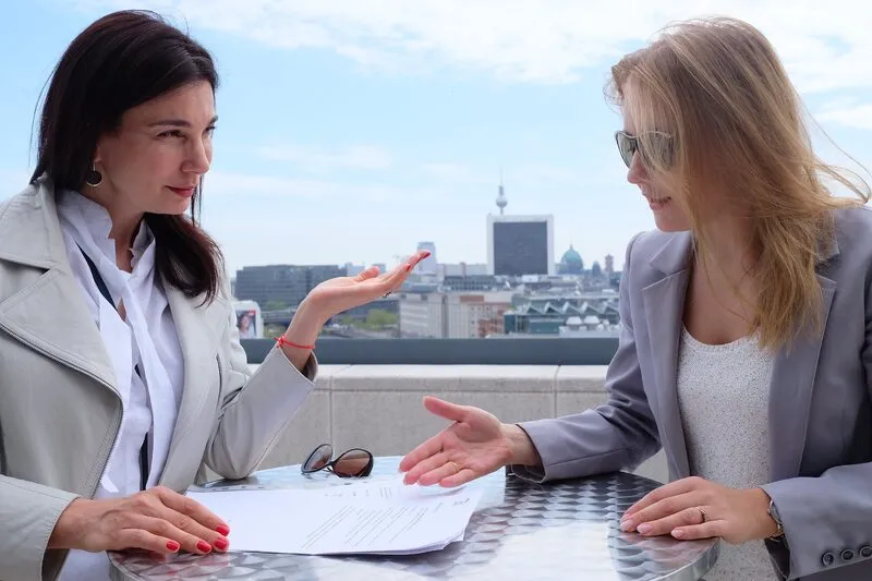 Two businesswomen negotiating at a table on a rooftop terrace